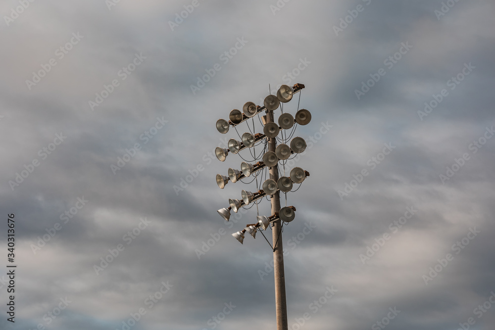 Low-angle shot of stadium lights under a cloudy sky at a sports field
