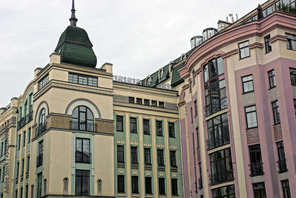 tall houses with green and pink windows on a city street against a gray sky