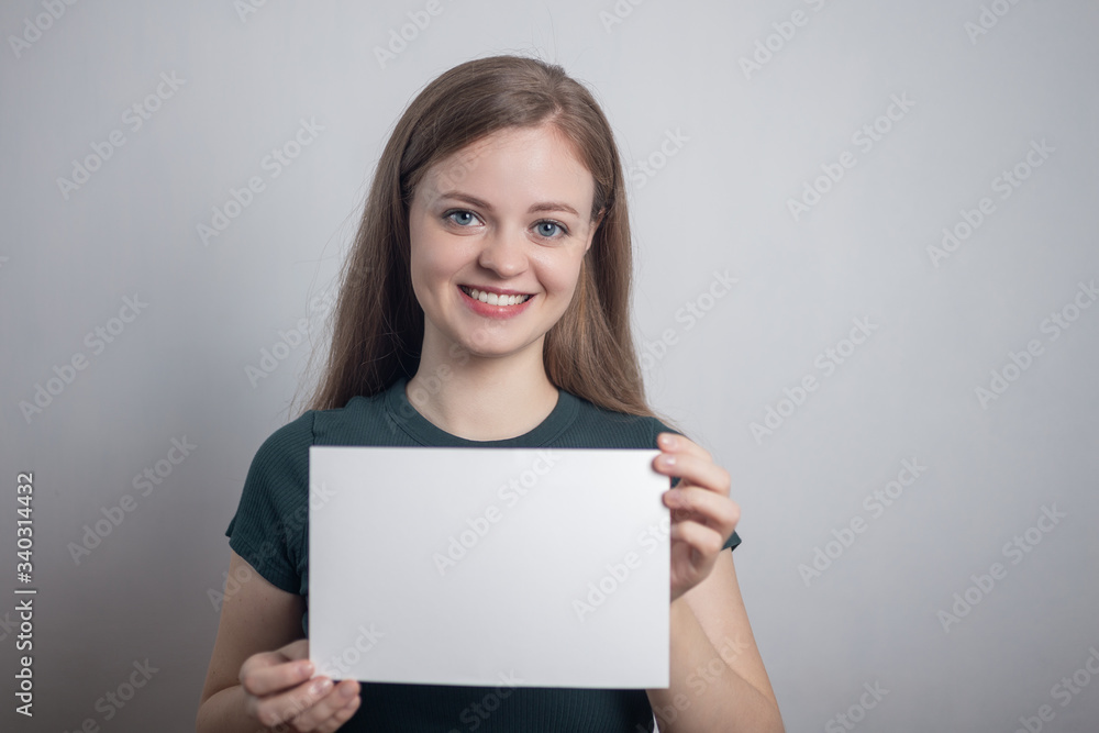 Smiling young Caucasian woman girl holding blank white paper sheet with copy space Smiling young Caucasian woman girl holding blank white paper sheet with copy space