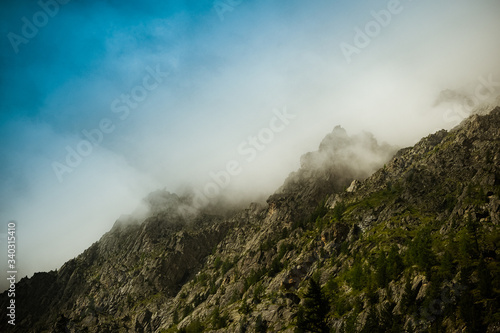mountain slope with forest and morning fog, clouds covered the rock ridge