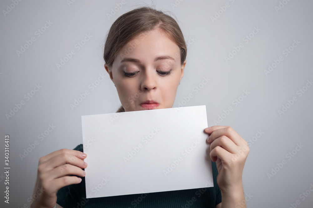 Smiling young Caucasian woman girl holding blank white paper sheet with copy space Smiling young Caucasian woman girl holding blank white paper sheet with copy space