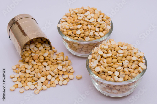 Group of a healthy roasted gram in a bowl with brass measuring jar on a white background