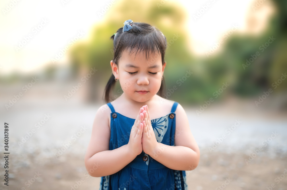 A cute little Asian girl prayed to God in the morning. The concept of prayer for faith, spirit, and religion A cute little Asian girl prayed to God in the morning. The concept of prayer for faith, spirit, and religion