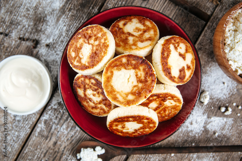 Top view on magnificent russian cottage cheese pancakes syrniki in a bowl, horizontal