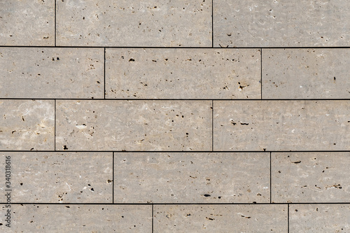 Modern stone facade texture of smooth natural stone plates at modern building facade in warm sunlight