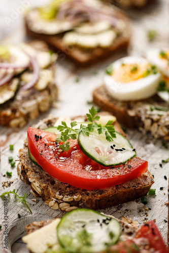 Buckwheat bread sandwich with tomato and cucumber on a wooden board. Close up view
