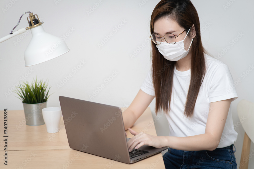 Asian woman is working from home during coronavirus or COVID-19 with laptops and computers at home, wearing protective mask, quarantine for coronavirus Asian woman is working from home during coronavirus or COVID-19 with laptops and computers at home, wearing protective mask, quarantine for coronavirus