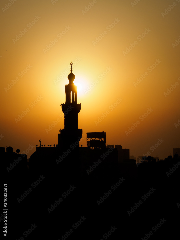 the sun hits the minaret of a mosque as the sun sets in Cairo