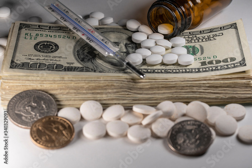 Stack of American money with medicine, pills and clinical thermometer on stack of Dollar cash