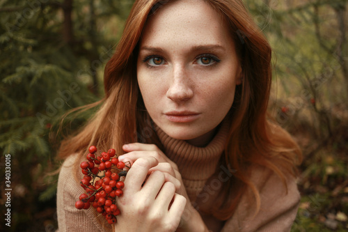 Foto Beautiful red head girl in sweater in forest