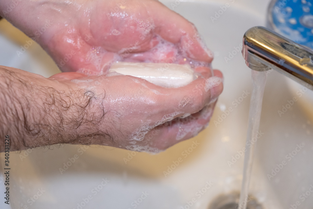 Fototapeta premium Personal hygiene and prevention of the coronavirus pandemic wash men's hands with soap and water.
