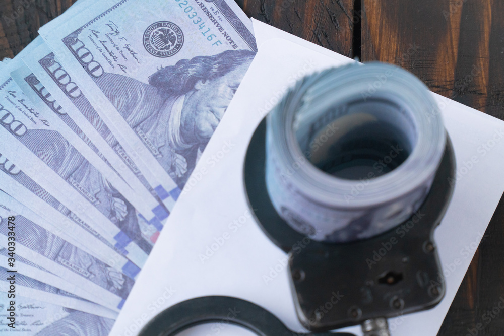twisted wad of dollars buttoned with handcuffs on wooden background, envelope with money twisted wad of dollars buttoned with handcuffs on wooden background, envelope with money