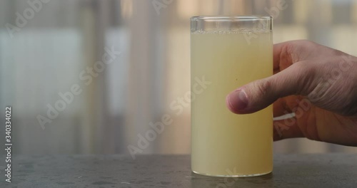 Slow motion man hand take lemon ginger lemonade into glass on concrete surface photo