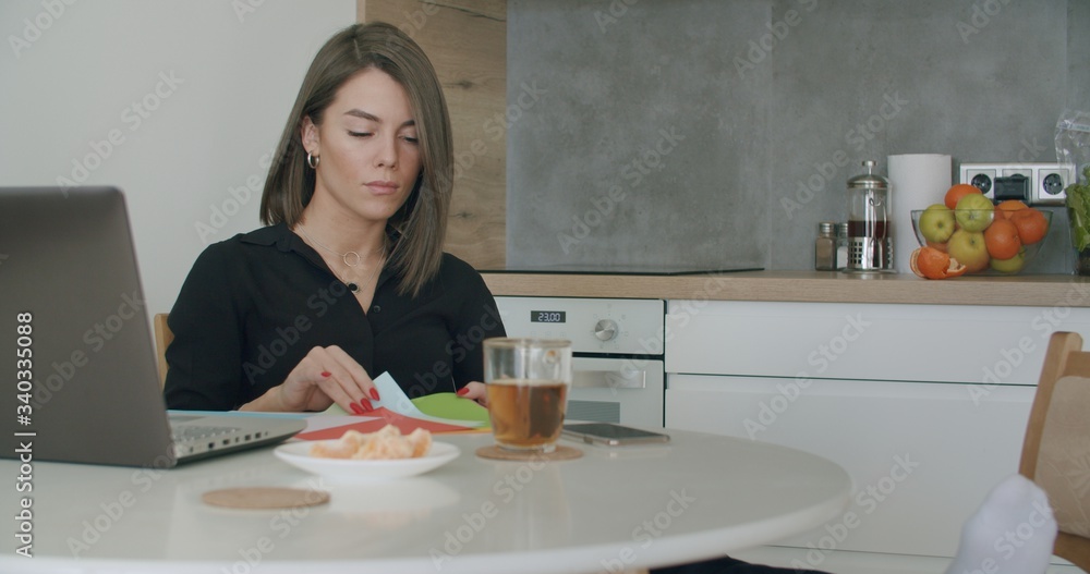 Woman working with papers sitting in kitchen at home. Woman working with papers sitting in kitchen at home.
