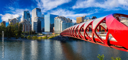 Φωτογραφία Peace Bridge across Bow River with Modern City Buildings in Background during a vibrant summer sunrise