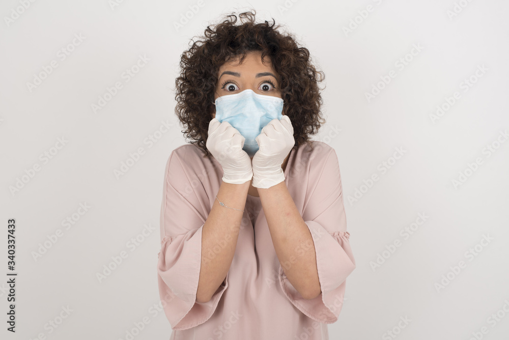 Studio shot of pleased lovely human wearing medical mask keeps hands together under chin, being in high spirit, likes friends idea for next day. Positive emotions. Studio shot of pleased lovely human wearing medical mask keeps hands together under chin, being in high spirit, likes friends idea for next day. Positive emotions.