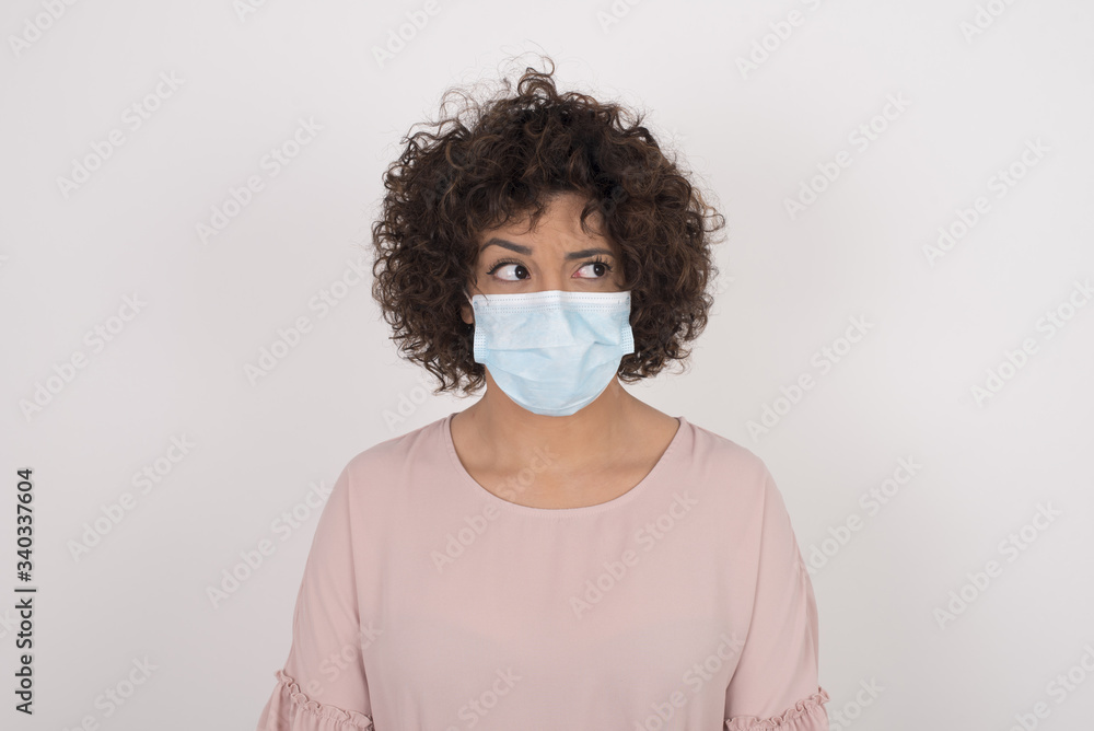 Photo of amazed puzzled young Caucasian female with ginger hair knot, curves lips and has worried look, sees something awful in front, isolated on white background, dressed in jean overalls. Photo of amazed puzzled young Caucasian female with ginger hair knot, curves lips and has worried look, sees something awful in front, isolated on white background, dressed in jean overalls.