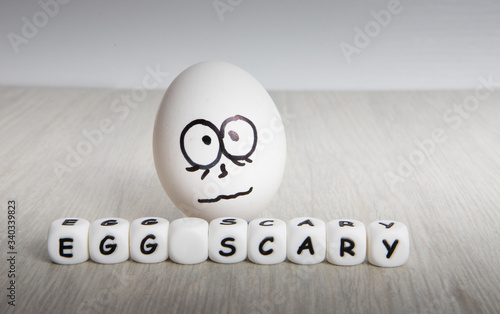 white egg with frightened face on white wooden background photo