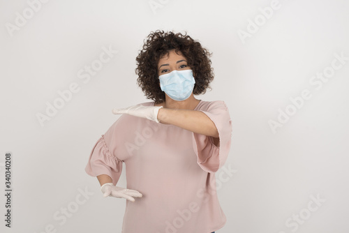 Blonde European woman wearing medical mask over isolated background gesturing with hands showing big and large size sign, measure symbol.  © Jihan