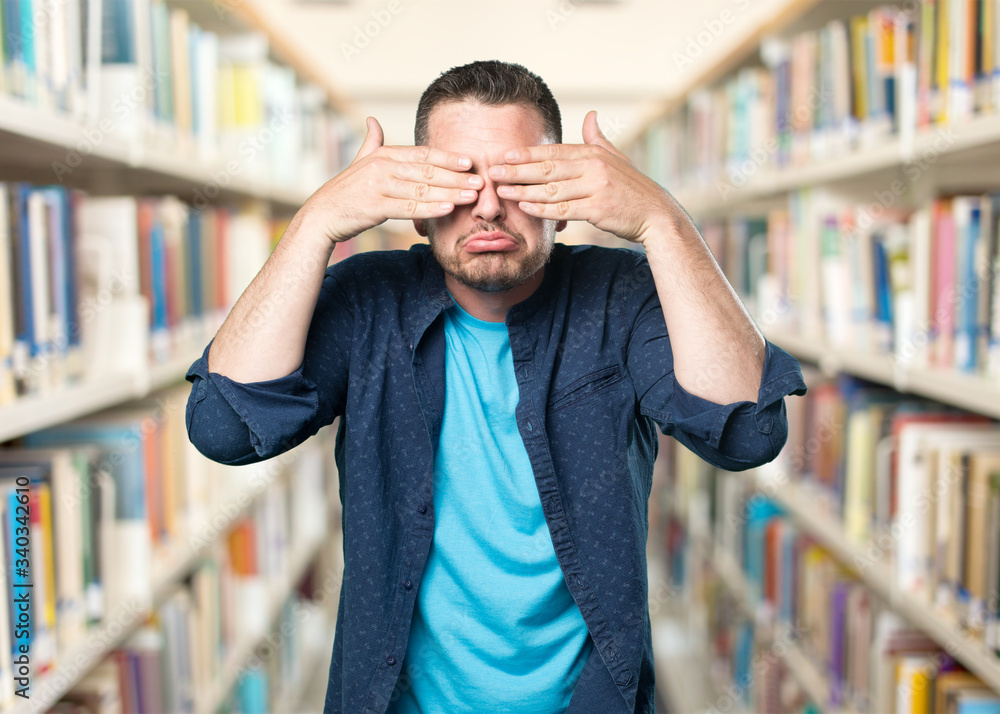 Young man wearing a blue outfit. Sad and covering his eyes with his hands. Young man wearing a blue outfit. Sad and covering his eyes with his hands.