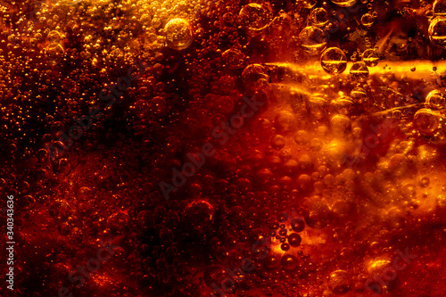 Close up view of the ice cubes in dark cola background. Texture of cooling sweet summer's drink with foam and macro bubbles on the glass wall. Fizzing or floating up to top of surface