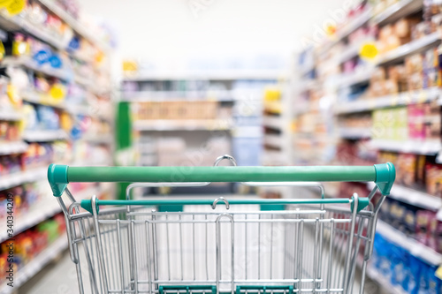 Background and wallpaper of shopping cart in supermarket departmentstore for choosing and buying grocery things at shelf. Time for shopping household goods, snacks, food, fruit, beverages and other.