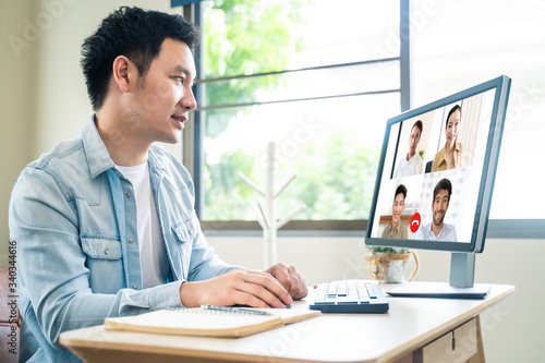 Asian business man talking to colleague team about plan in video conference. Group of business people using computer for remote online meeting in video call conference. Smart working from home. © Kawee