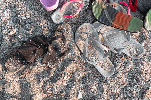 Summer slippers lying on a sandy beach with shells. Slippers covered with shells. Summer day.