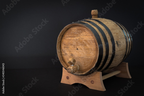 A small, oak bourbon barrel that is used to age bourbon whiskey on a black background. Typically corn whiskey is used in the barrels to make bourbon. Bourbon making is a tradition in southern US.