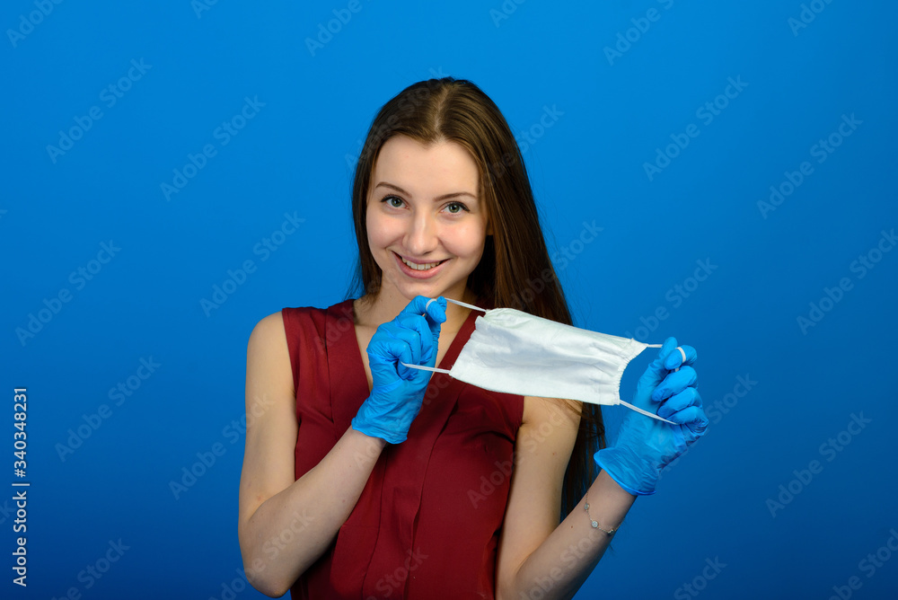 Girl in protective medical mask and blue gloves on blue background. close-up portrait of a woman in a transparent mask. way to protect against coronavirus. Covid-2019, Pandemic 2020 Girl in protective medical mask and blue gloves on blue background. close-up portrait of a woman in a transparent mask. way to protect against coronavirus. Covid-2019, Pandemic 2020