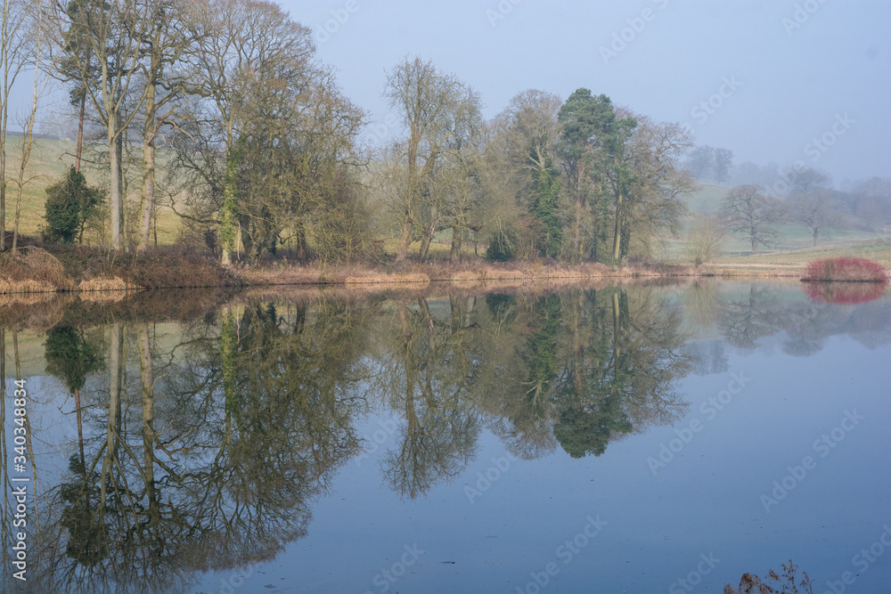 Fototapeta premium View of a lake in the English countryside on an autumn morning with reflected trees