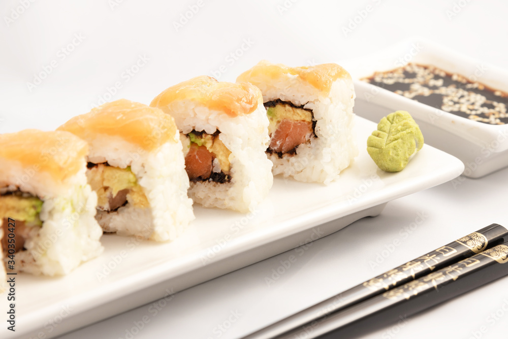 Sushi roll with pink salmon wrap, grilled salmon, Philadelphia cheese and avocado. White container and black chopsticks. Sushi roll with pink salmon wrap, grilled salmon, Philadelphia cheese and avocado. White container and black chopsticks.