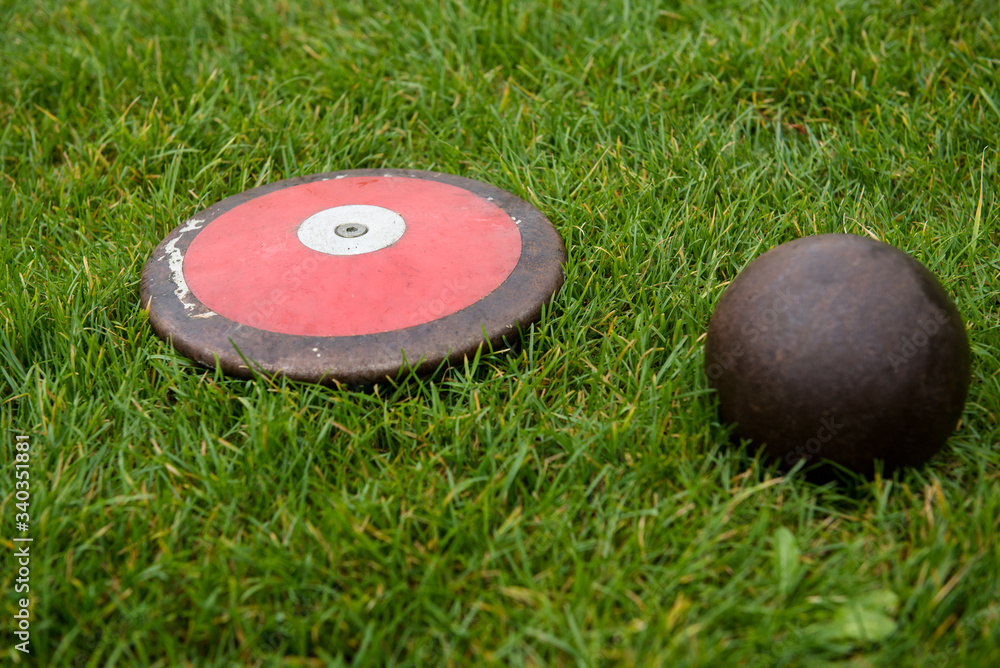 Naklejka premium Discus and shot put on the grass, track and field equipment