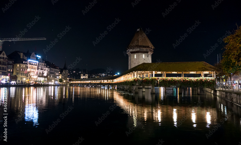 Illuminated Lucerne and Chapel Bridge reflect on the river