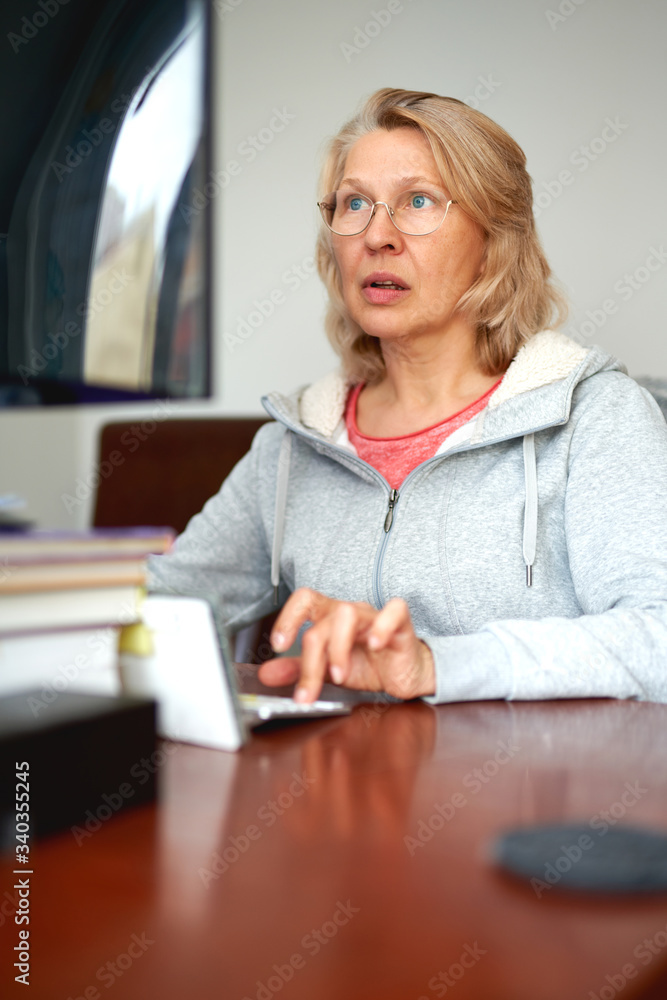 Woman middle aged in glasses using laptop typing email working at home office, lady searching information on internet or communicating online Woman middle aged in glasses using laptop typing email working at home office, lady searching information on internet or communicating online