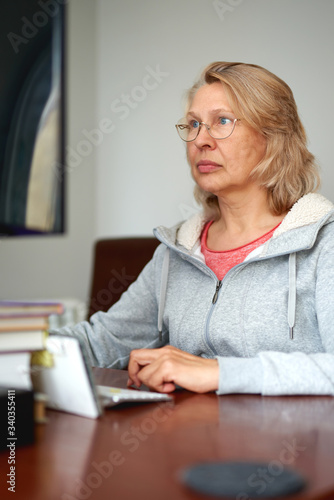 Woman middle aged in glasses using laptop typing email working at home office, lady searching information on internet or communicating online