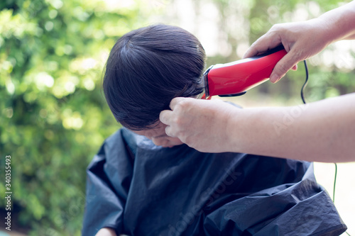 Grandma was cutting hair for her nephew at home in the garden.