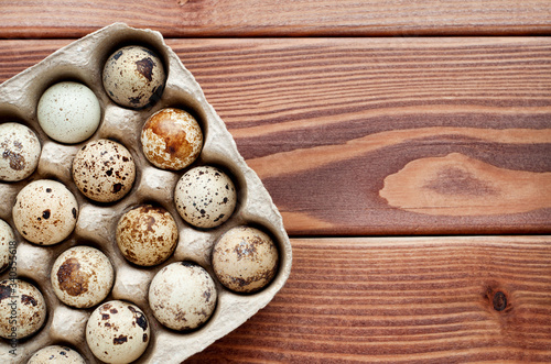 Quail eggs in a carton on a wooden background. Healthy food.