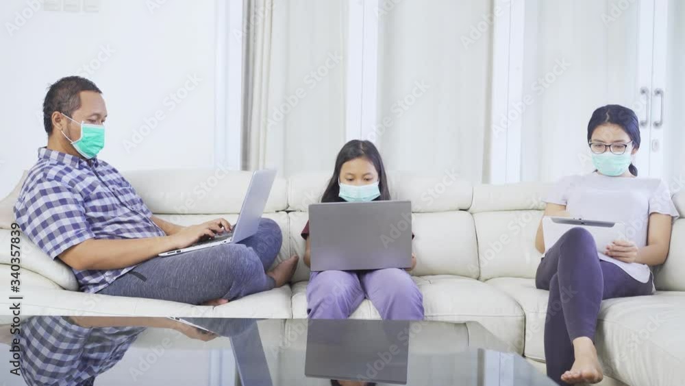 Coronavirus concept. Young family using laptop and digital tablet while relaxing together on the couch during quarantine at home. Shot in 4k resolution Coronavirus concept. Young family using laptop and digital tablet while relaxing together on the couch during quarantine at home. Shot in 4k resolution