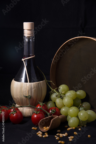 Foto fiasco di vino con uva grano pomodori e setaccio