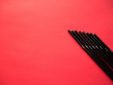 Black plastic single use straws isolated on red background. Top view.
