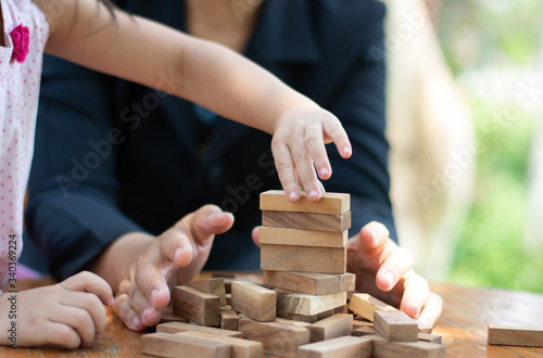 hands of a child playing with a wooden toy supervise by a businessman instructor: Play and learn