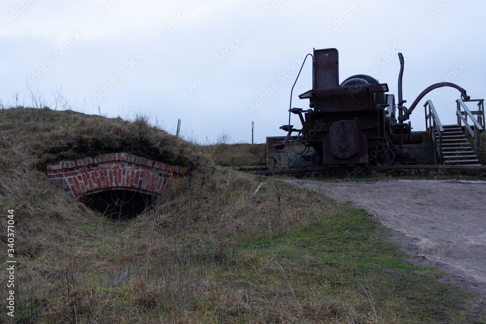 Fototapeta premium The case and the turning mechanism of a large old cannon from the time of the Russian Empire near fortifications in the historical fort Suomenlinna, in Helsinki, Finland, autumn day