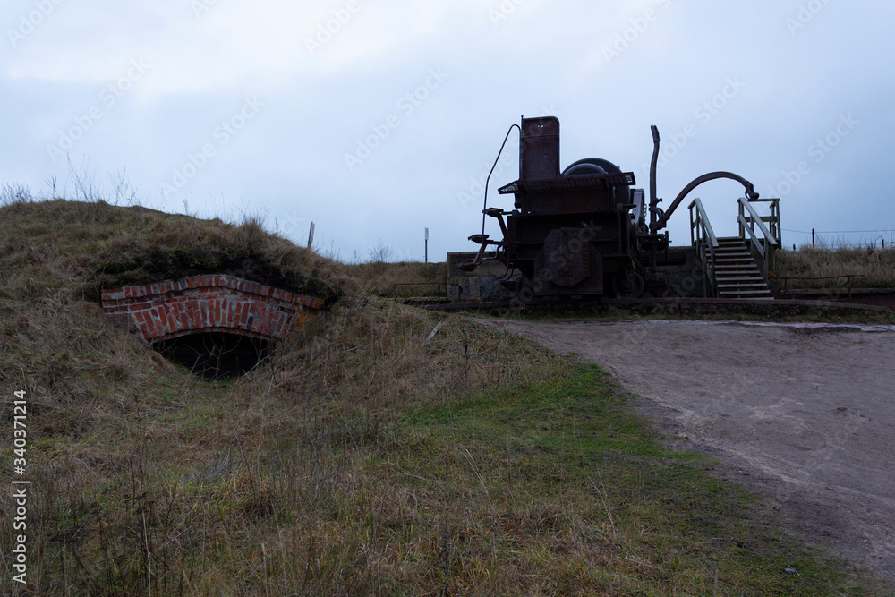 Fototapeta premium The case and the turning mechanism of a large old cannon from the time of the Russian Empire near fortifications in the historical fort Suomenlinna, in Helsinki, Finland, autumn day