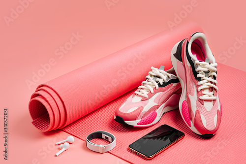 Bright fashion sneakers with smartphone, fitness bracelet and pink yoga mat. App for training indoors. Online Fitness program. Home online workout. © igishevamaria