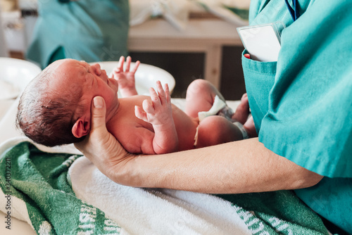 Doctor treats a newborn baby he's holding in his hands photo