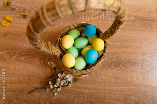 painted eggs in a basket on a wooden background