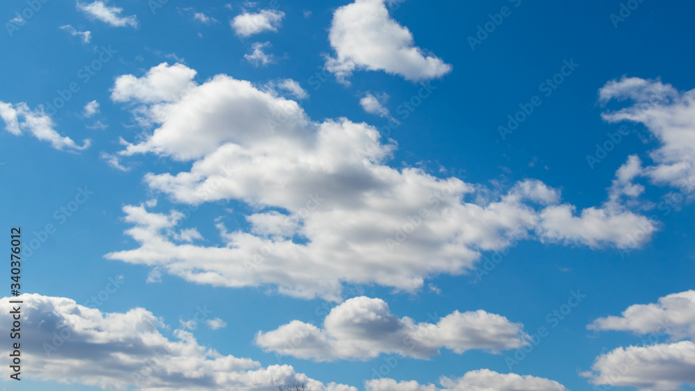 Obraz premium White clouds of unusual shape in the blue sky on a beautiful day