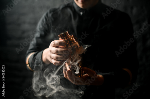 Close-up of bartender's hands which holds smoky steel shaker.