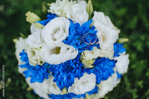 Wedding gold rings lie on a bouquet of white eustomas and blue asters. Photography, concept. photo